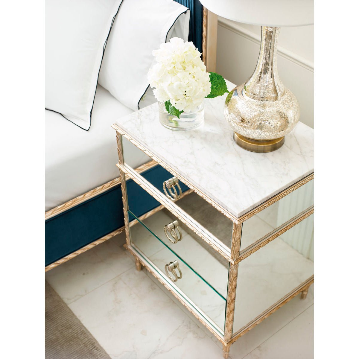 Gold nightstand in bedroom with decorative items.