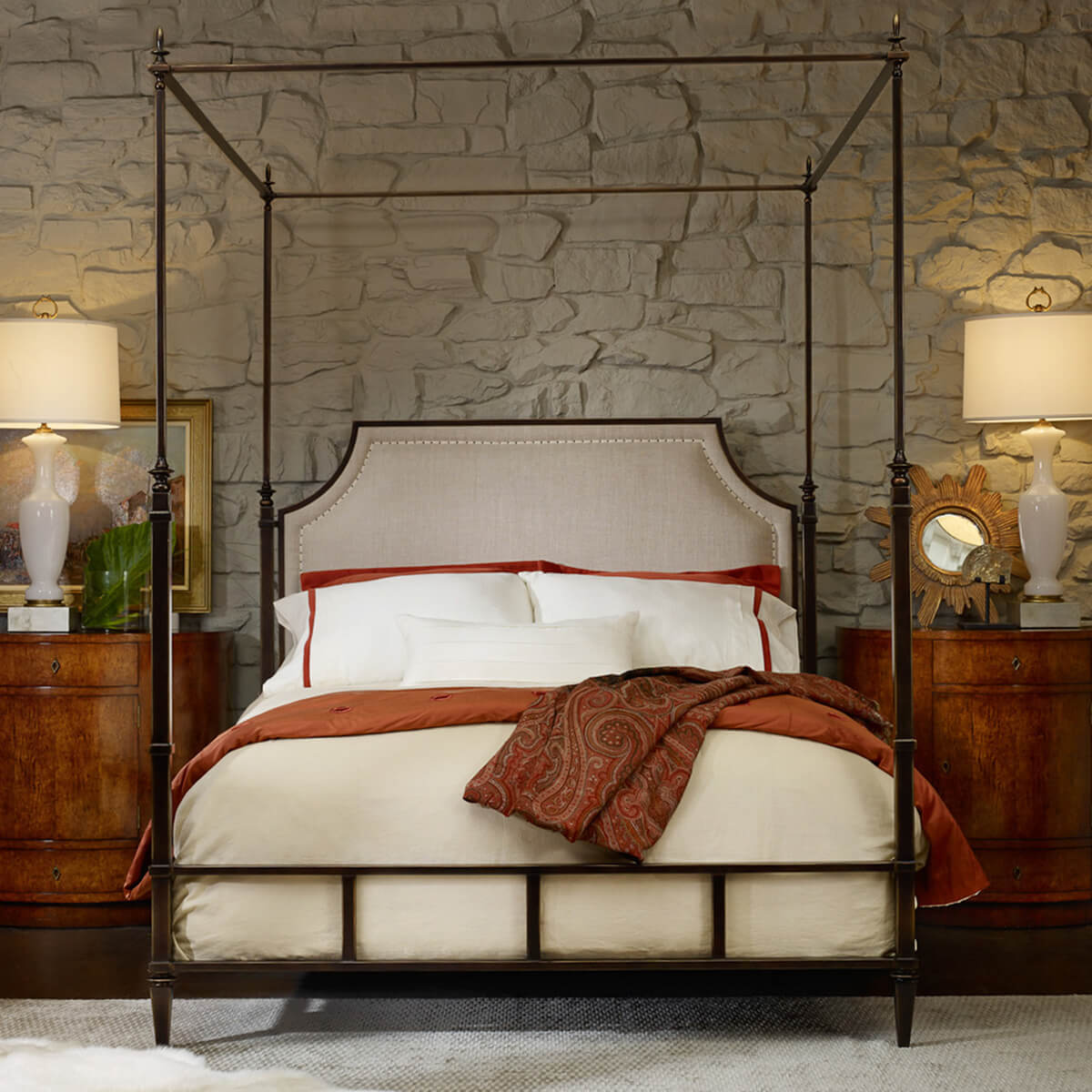 Queen metal canopy bed in rustic stone-wall bedroom.