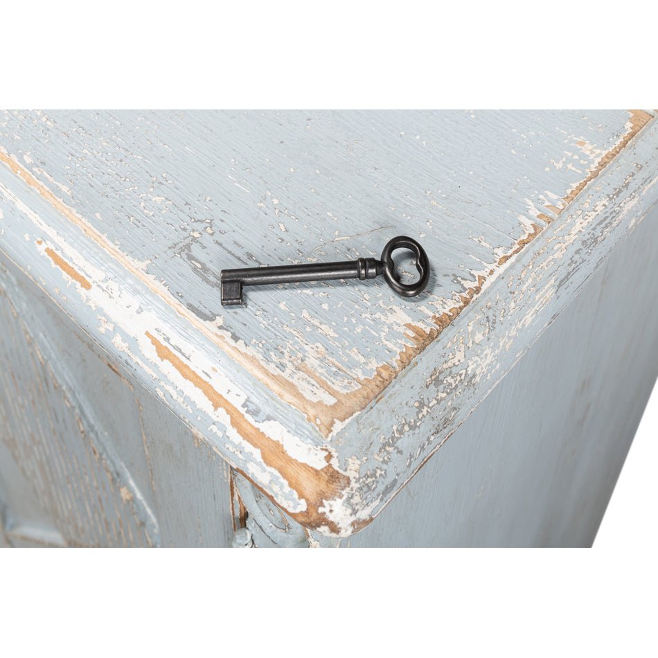 Antique key on blue painted sideboard corner.