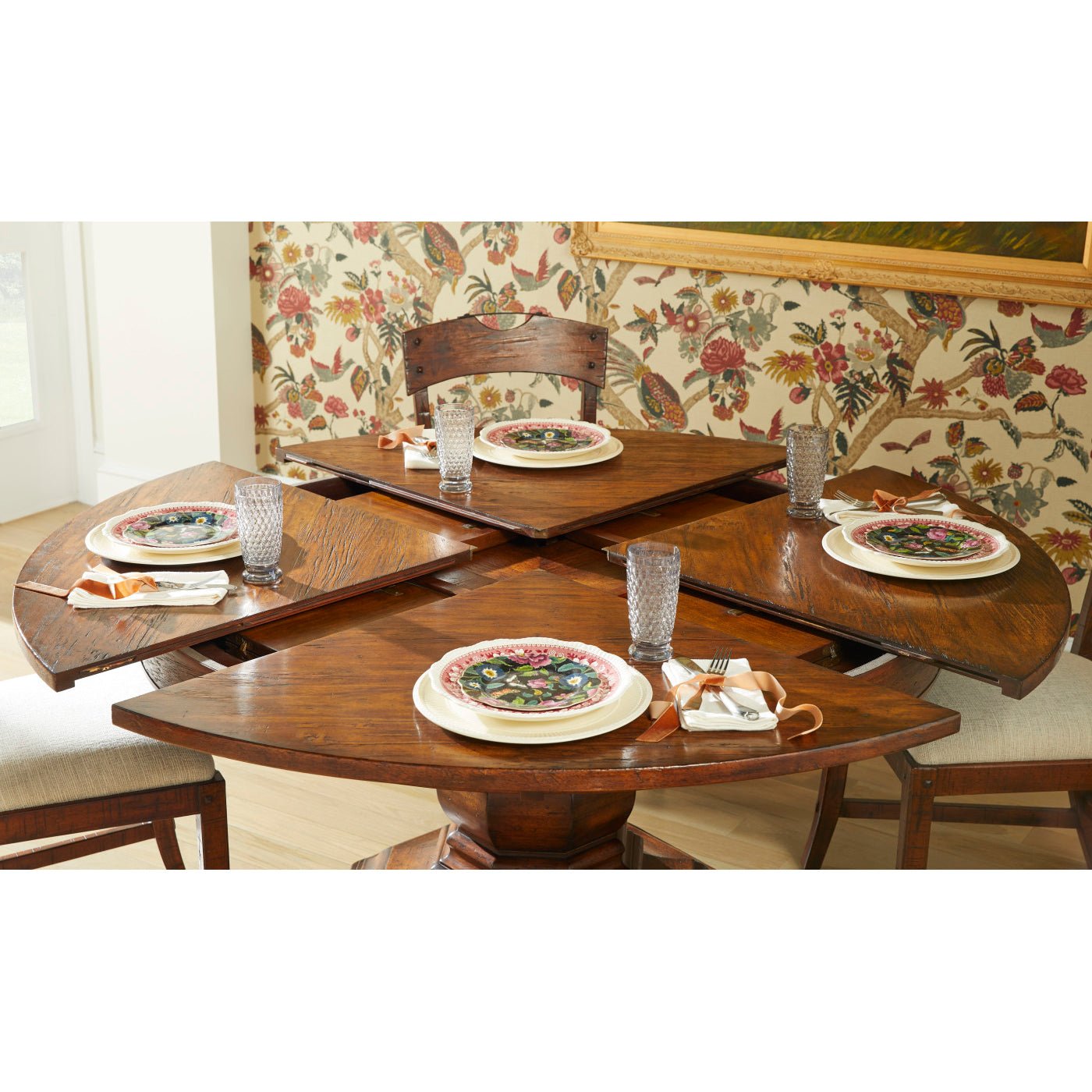 Partly extended round dining table with place settings.