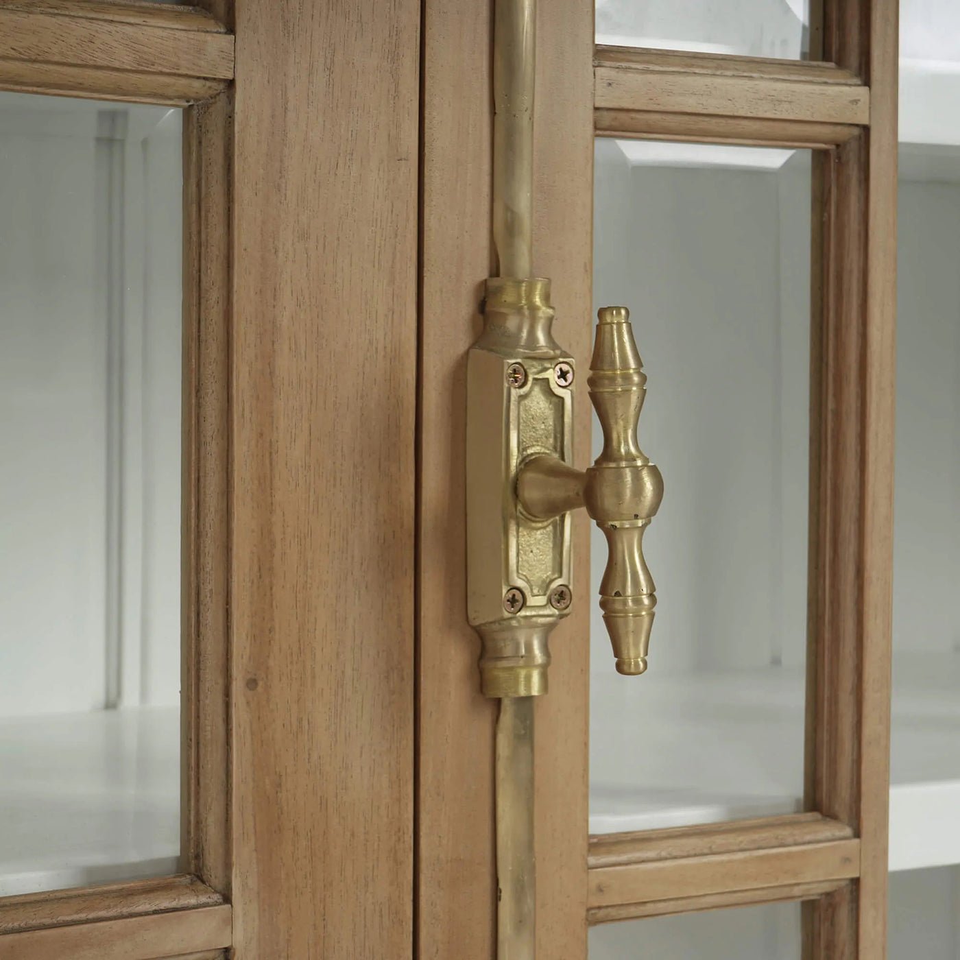Close-up of credenza's brass handle and glass doors.