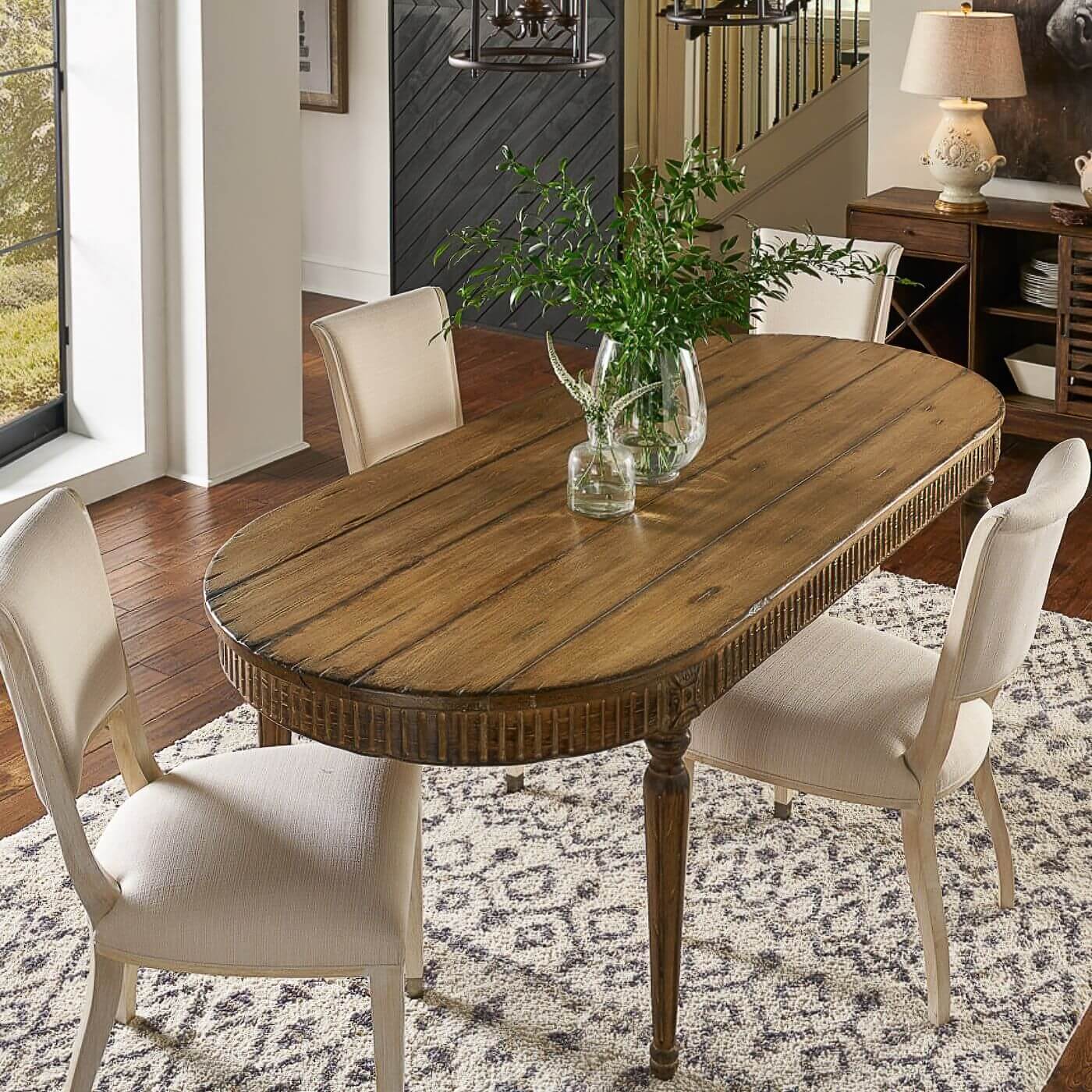 Oval dining table with chairs in dining room setting.