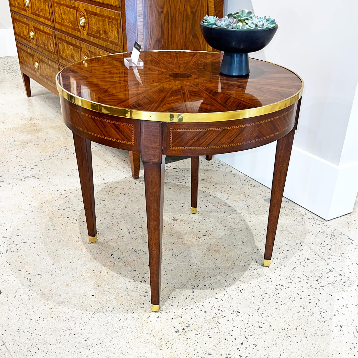 Parquetry side table displayed in showroom with decorative piece.