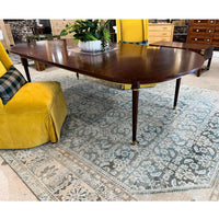 French walnut dining table on patterned rug with yellow chairs.