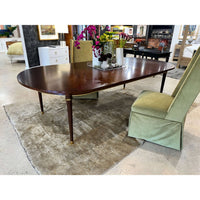 French walnut dining table in room with green chairs.