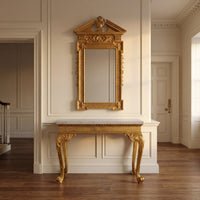 George II giltwood mirror above elegant console in bright room.