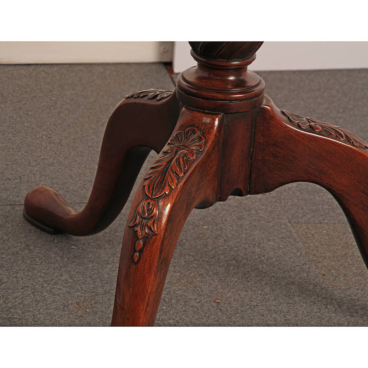 Close-up of carved legs on mahogany dumbwaiter.