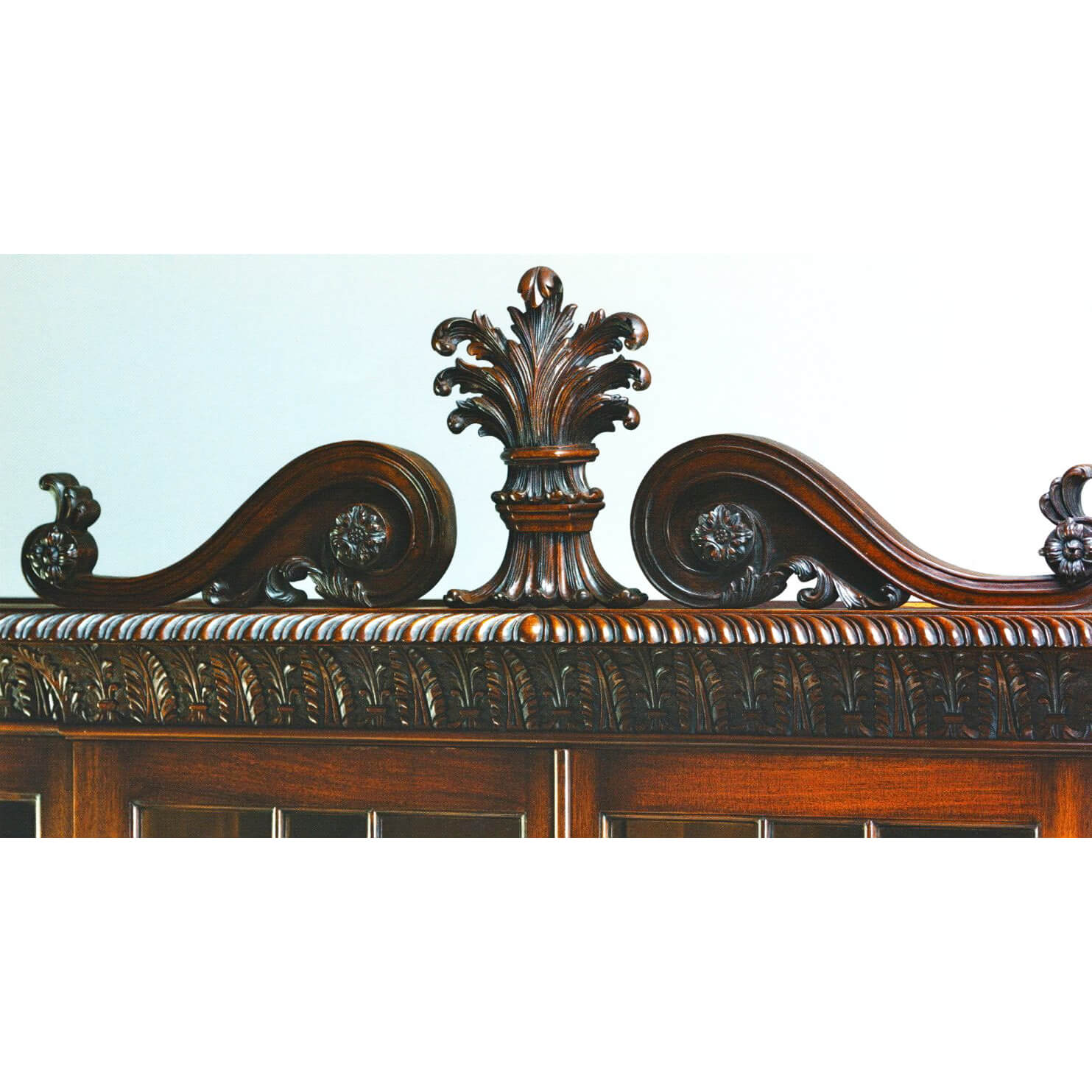 Top detail of mahogany breakfront bookcase, ornate carving.