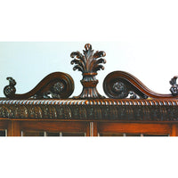 Top detail of mahogany breakfront bookcase, ornate carving.