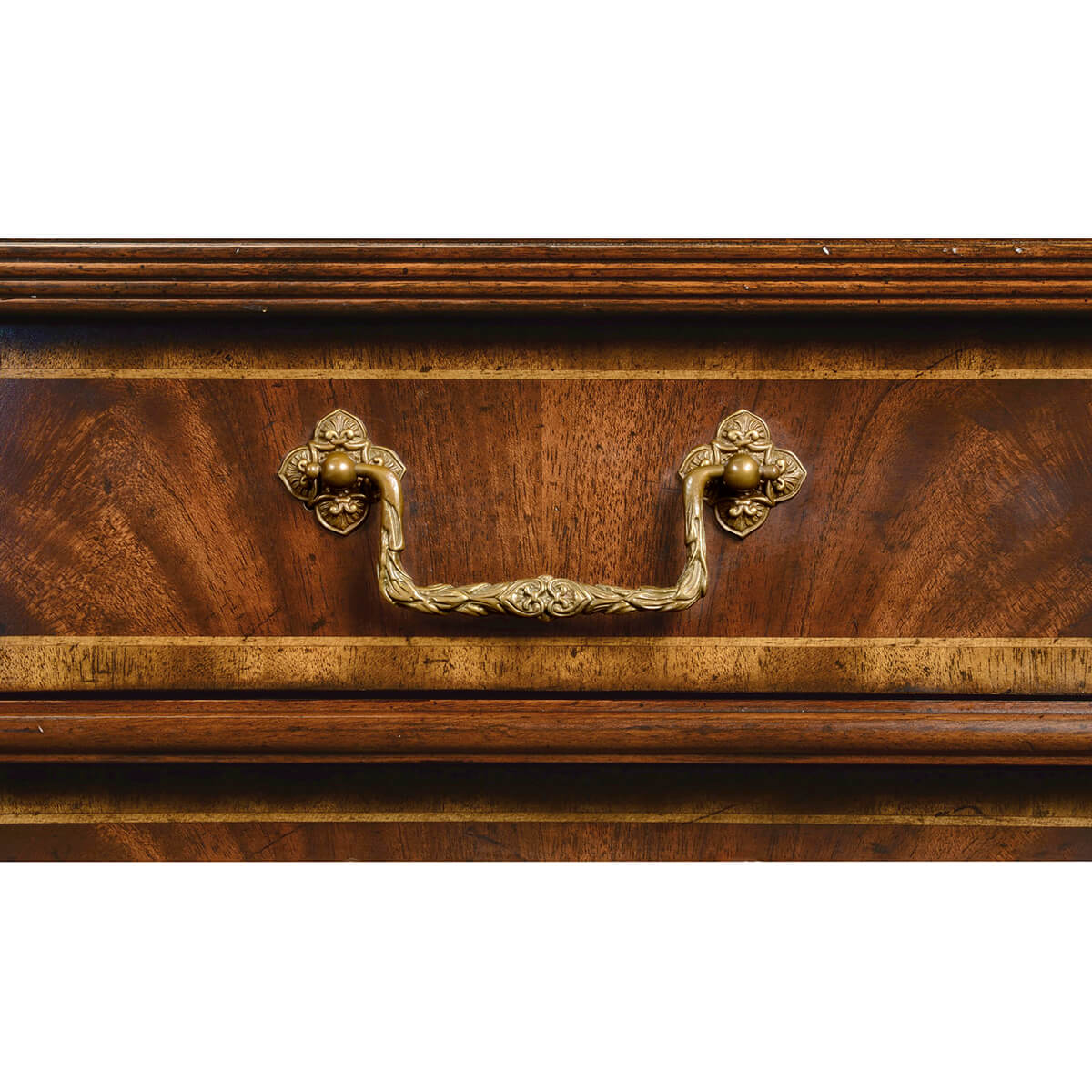 Close-up of ornate handle on mahogany chest drawer.