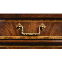 Close-up of ornate handle on mahogany chest drawer.