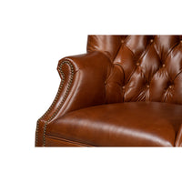 Close-up of arm and tufting on leather wingchair.