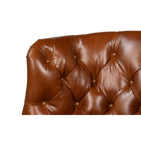 Close-up of tufted backrest on leather wingchair.