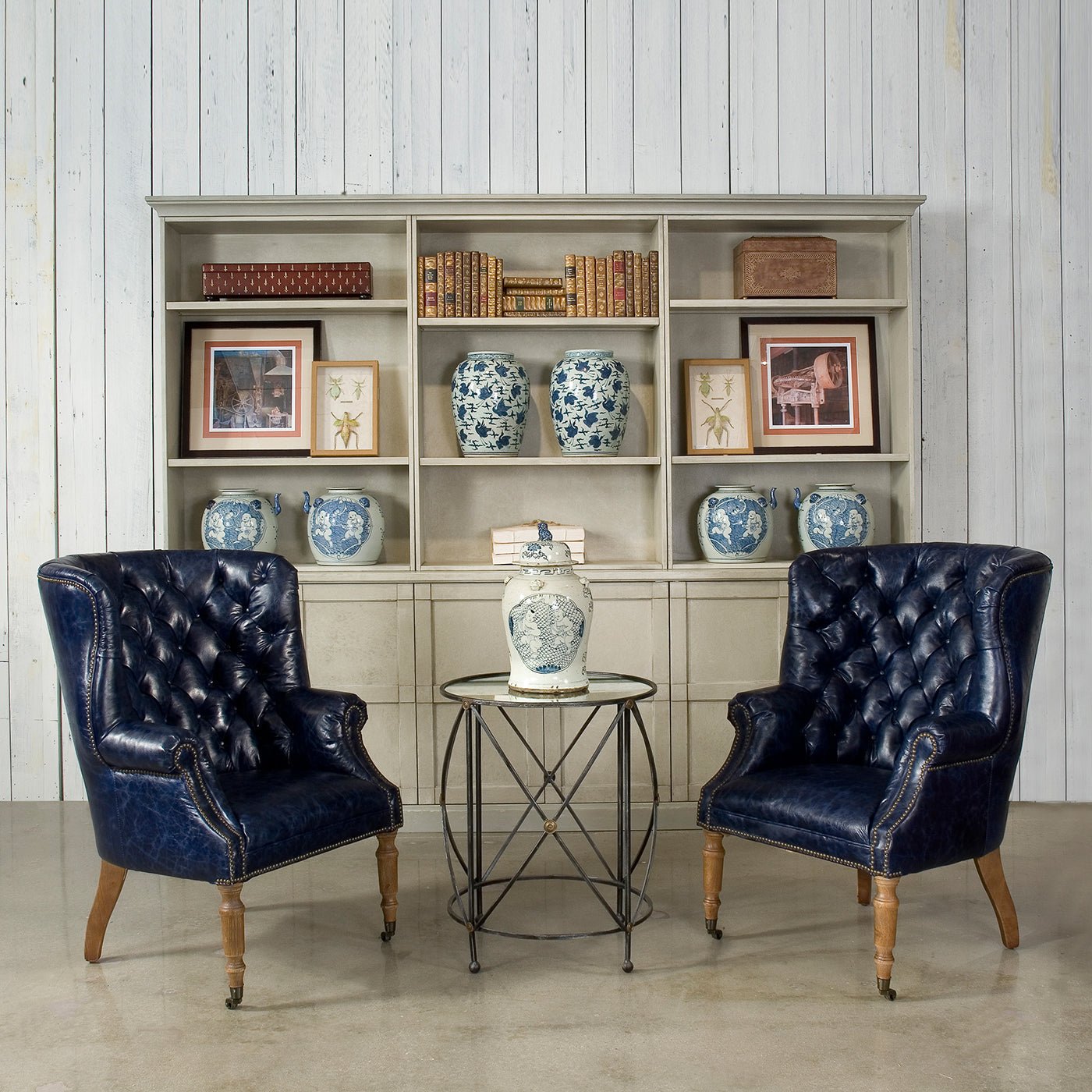 Pair of blue wingchairs in front of bookshelf.