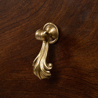 Close-up of brass handle on mahogany chest drawer.