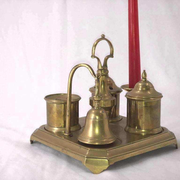 Side view of brass inkwell set with red candle.