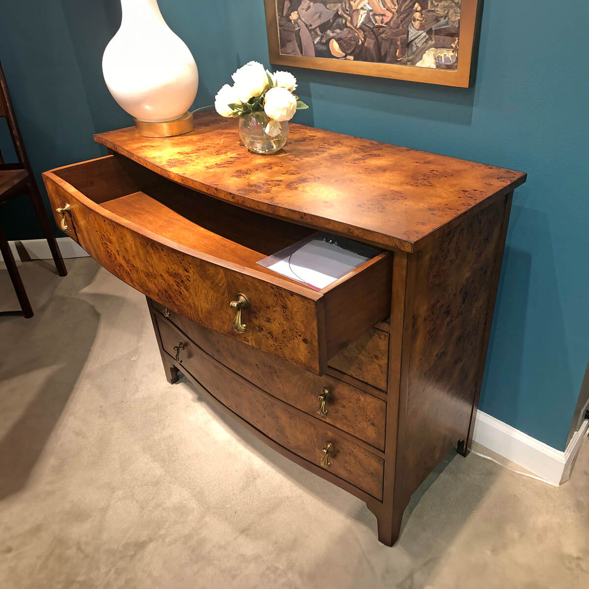 Open drawer in burl bowfront chest of drawers.