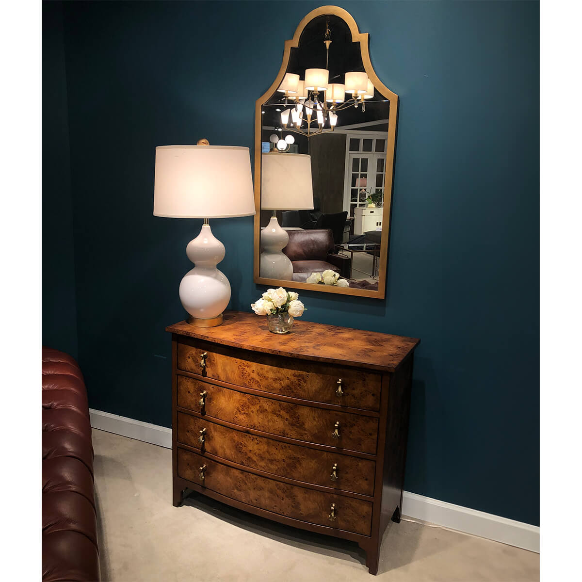 Dresser beneath elegant mirror with lamp and decor.