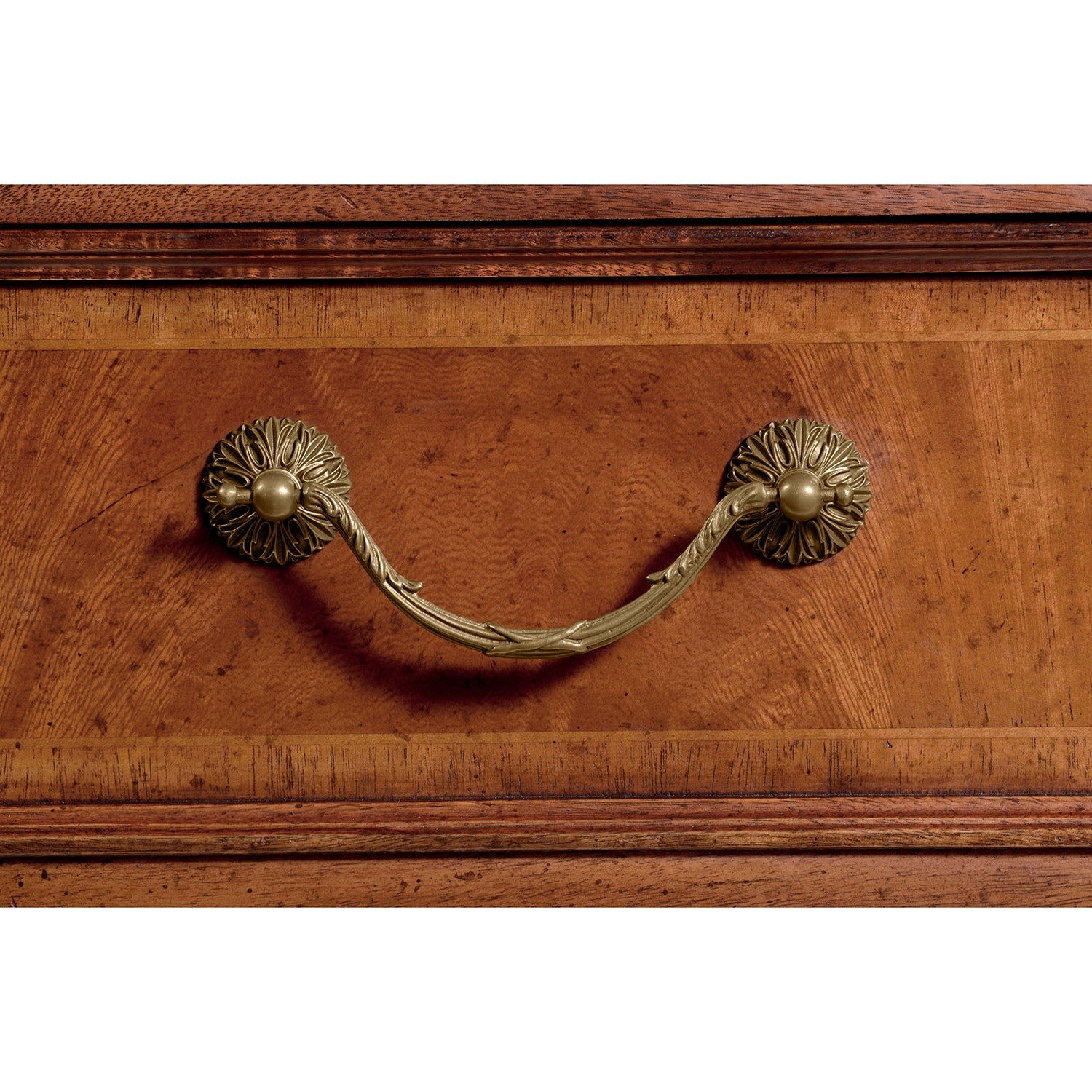 Detailed view of antique brass drawer handle on desk.