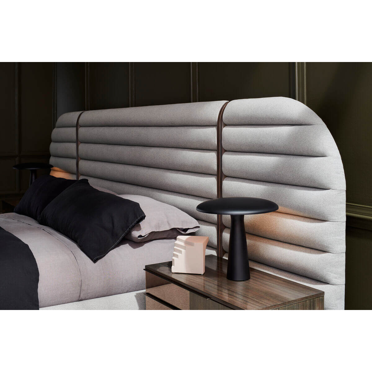 Gray channeled king bed headboard with nightstand and lamp.