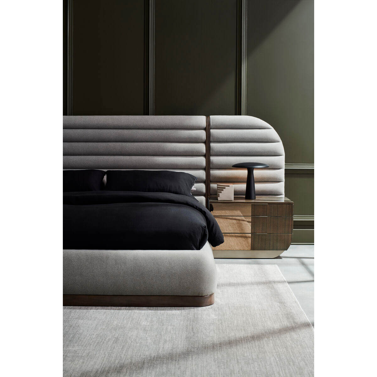 Side view of gray channeled king bed and nightstand.