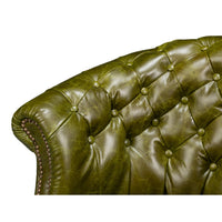 Green leather barrel back chair, backrest tufting detail.