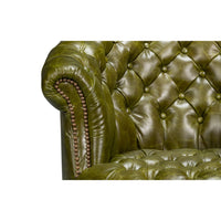 Green leather barrel back chair, armrest and tufting detail.