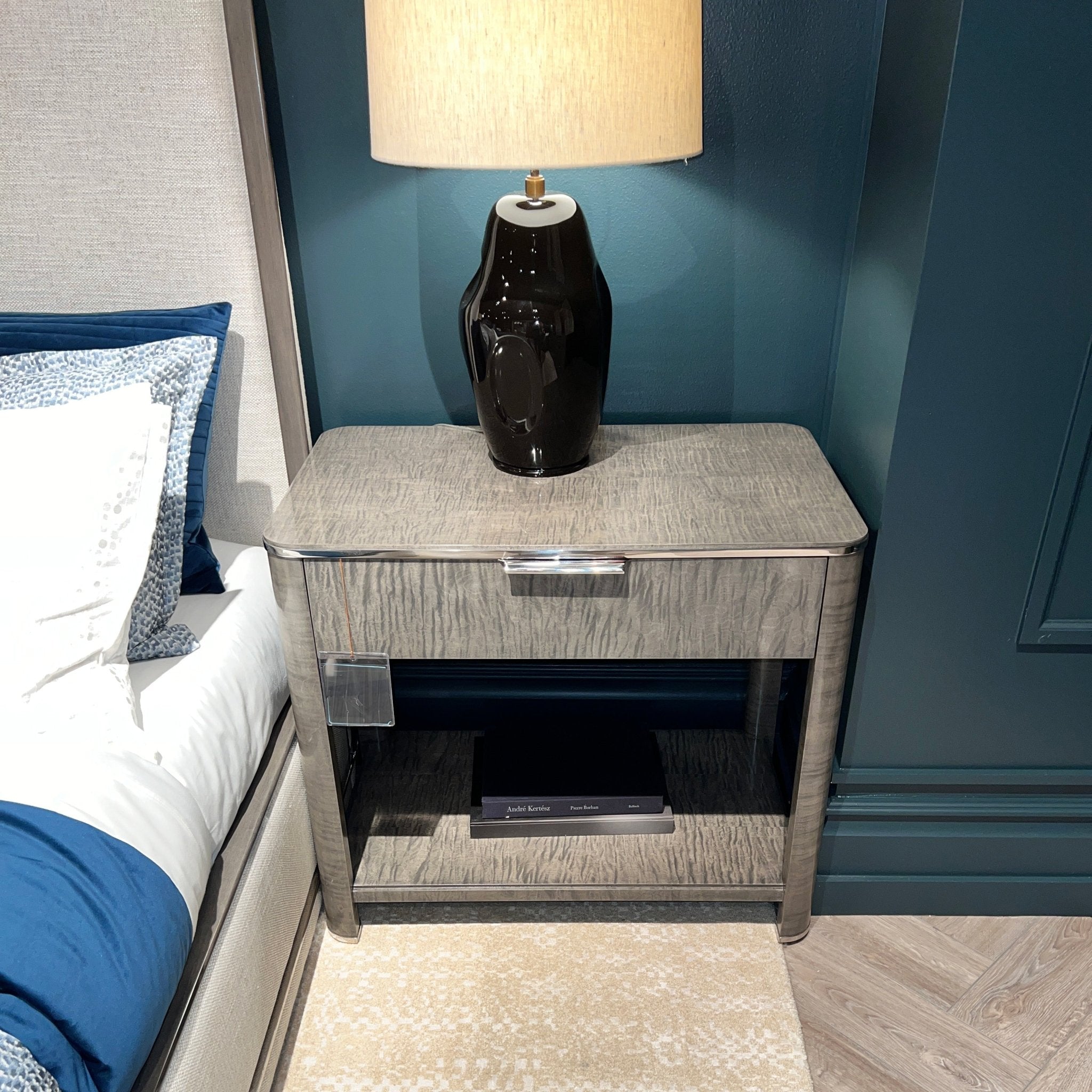Nightstand with lamp beside bed, art deco style.