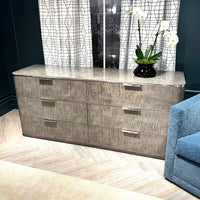 Dresser in room with flower vase, blue chair visible.