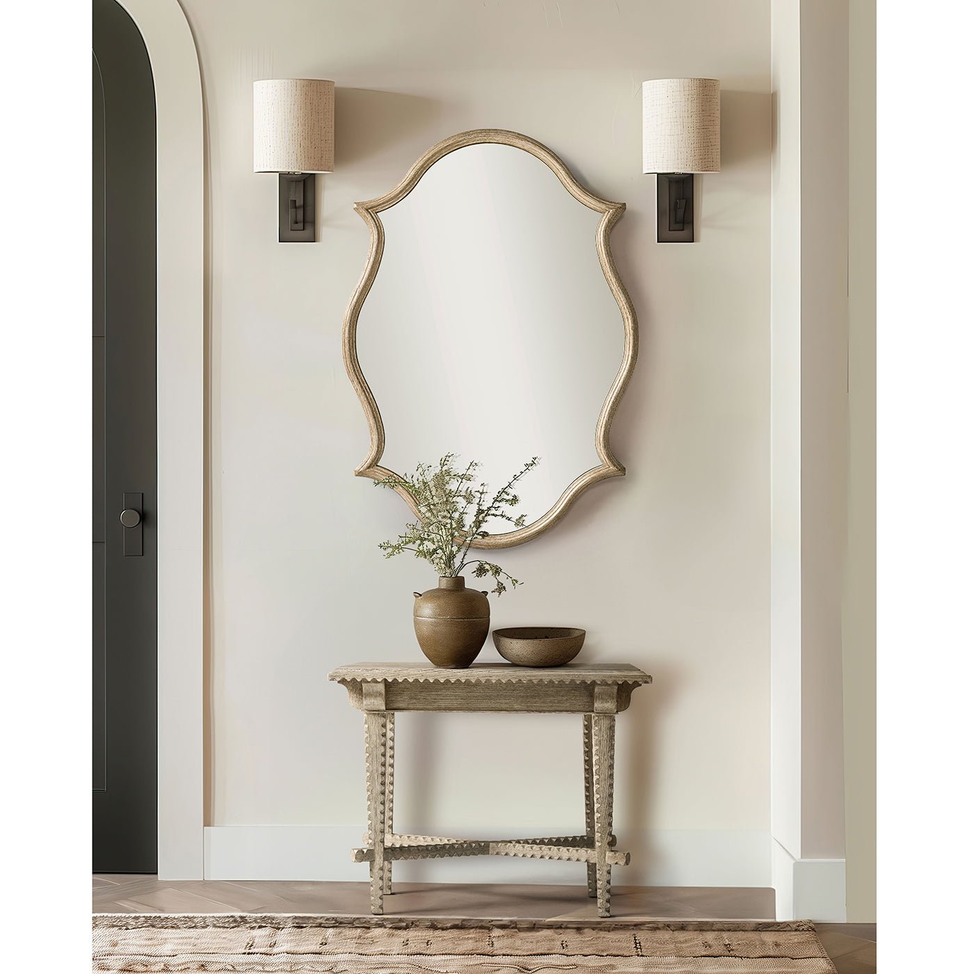 Greyed oak end table styled under mirror with decor.