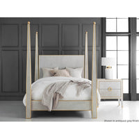 Grey four poster bed in a stylish, dark-paneled room.