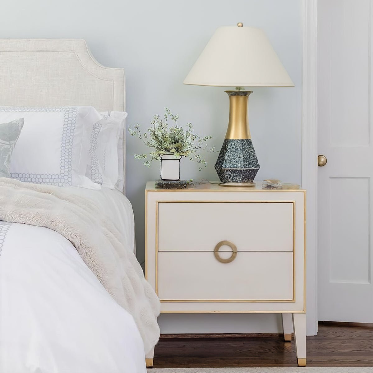 Cream nightstand styled in bedroom with lamp and decor.