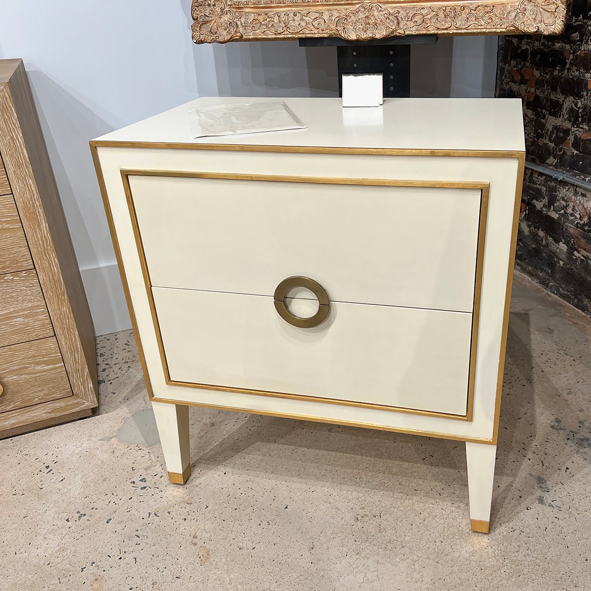 Cream nightstand close-up in showroom with textured floor.
