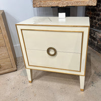 Cream nightstand close-up in showroom with textured floor.