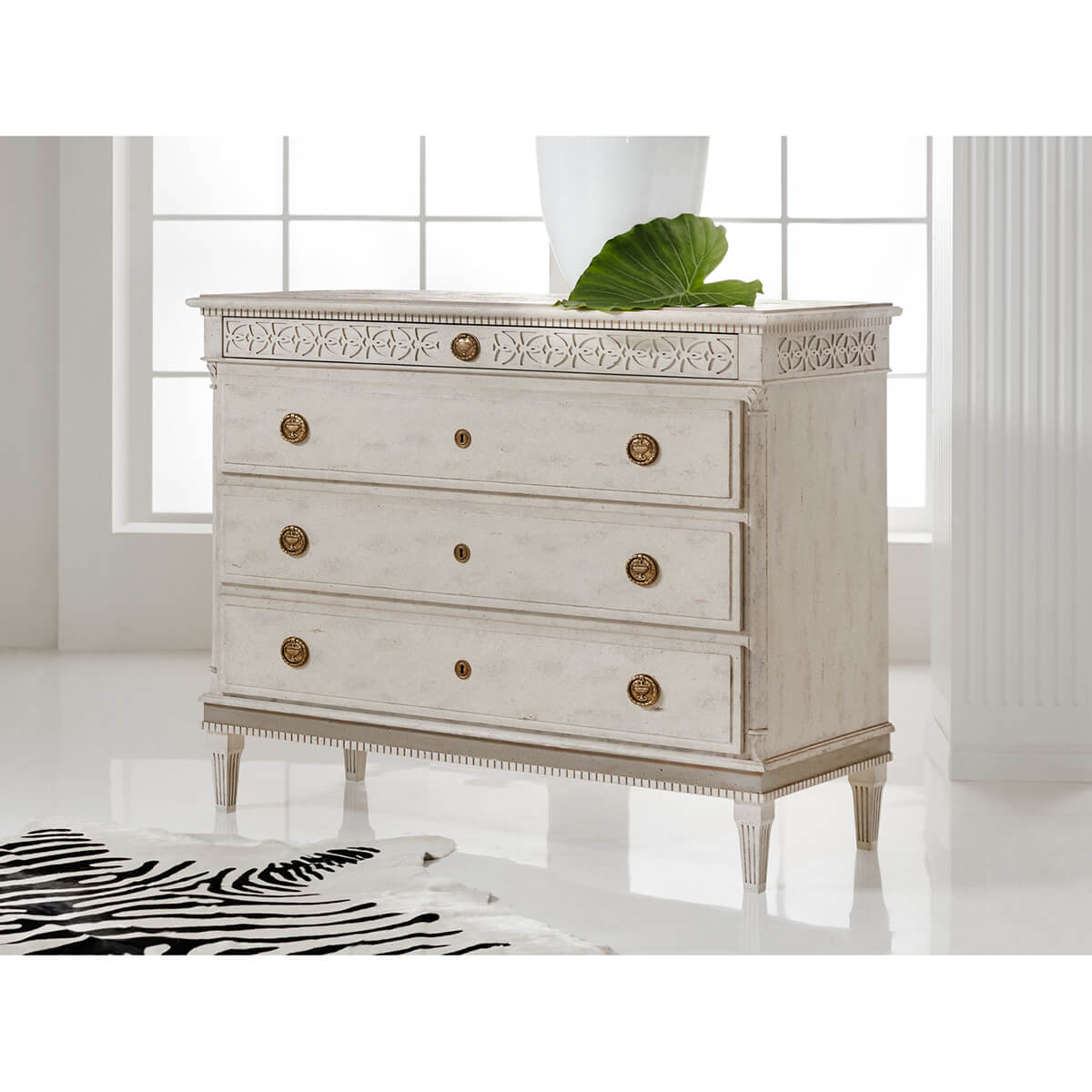 Swedish dresser in bright room with decorative top detail.
