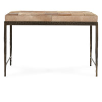 Front view of the Canyon Sand hair-on-hide bench showing its tan patchwork cushion and embossed iron apron