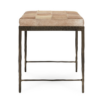 End view of the Canyon Sand hair-on-hide bench showing tapered iron legs, low crossbars and a tan seat