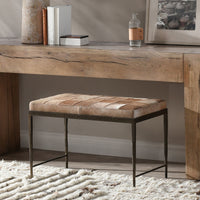 Canyon Sand hair-on-hide bench beneath a wood console, with its tan patchwork seat and slim iron frame
