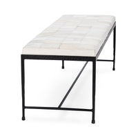 End view of the Dusty Cream hair-on-hide bench showing its patchwork seat and open black iron base