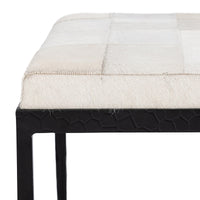 Close-up of the Dusty Cream bench showing stitched hair-on-hide squares, cushion edge and textured iron apron