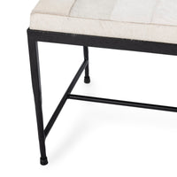 Close-up of the Dusty Cream bench showing a tapered black iron leg and low stretcher beneath the seat