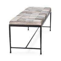 End view of the Sparrow Gray hair-on-hide bench showing the patchwork seat and open iron base