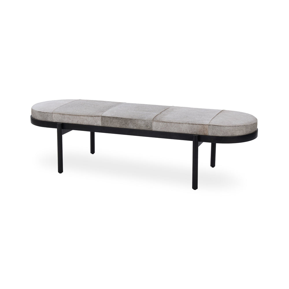 Gray hair-on-hide bench at an angle, with an oval patchwork seat, black iron rim and slender legs