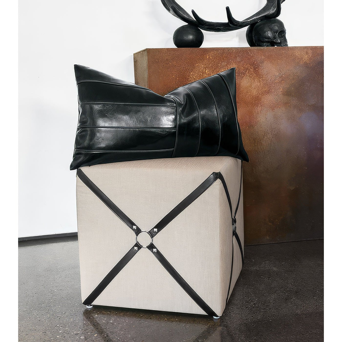 Harness cube ottoman with decorative pillow on top.