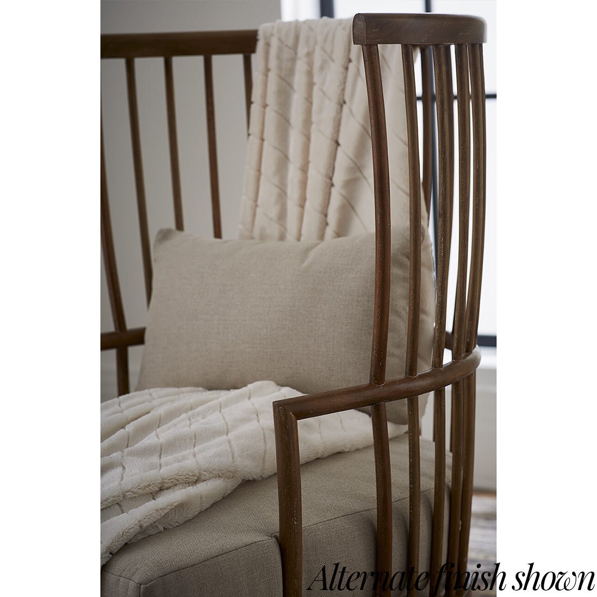 Close-up of high-back spindle armchair, beige cushion.