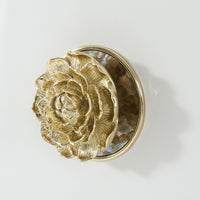 Detailed view of gold floral knob on sideboard.