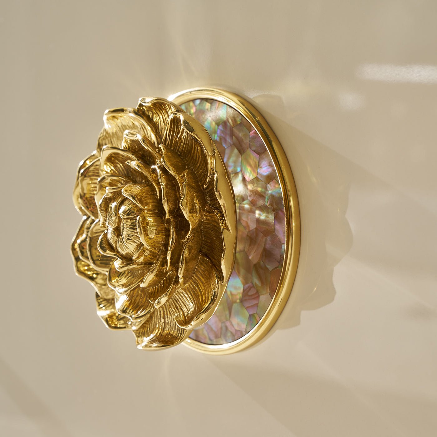 Close-up gold floral knob on white sideboard.