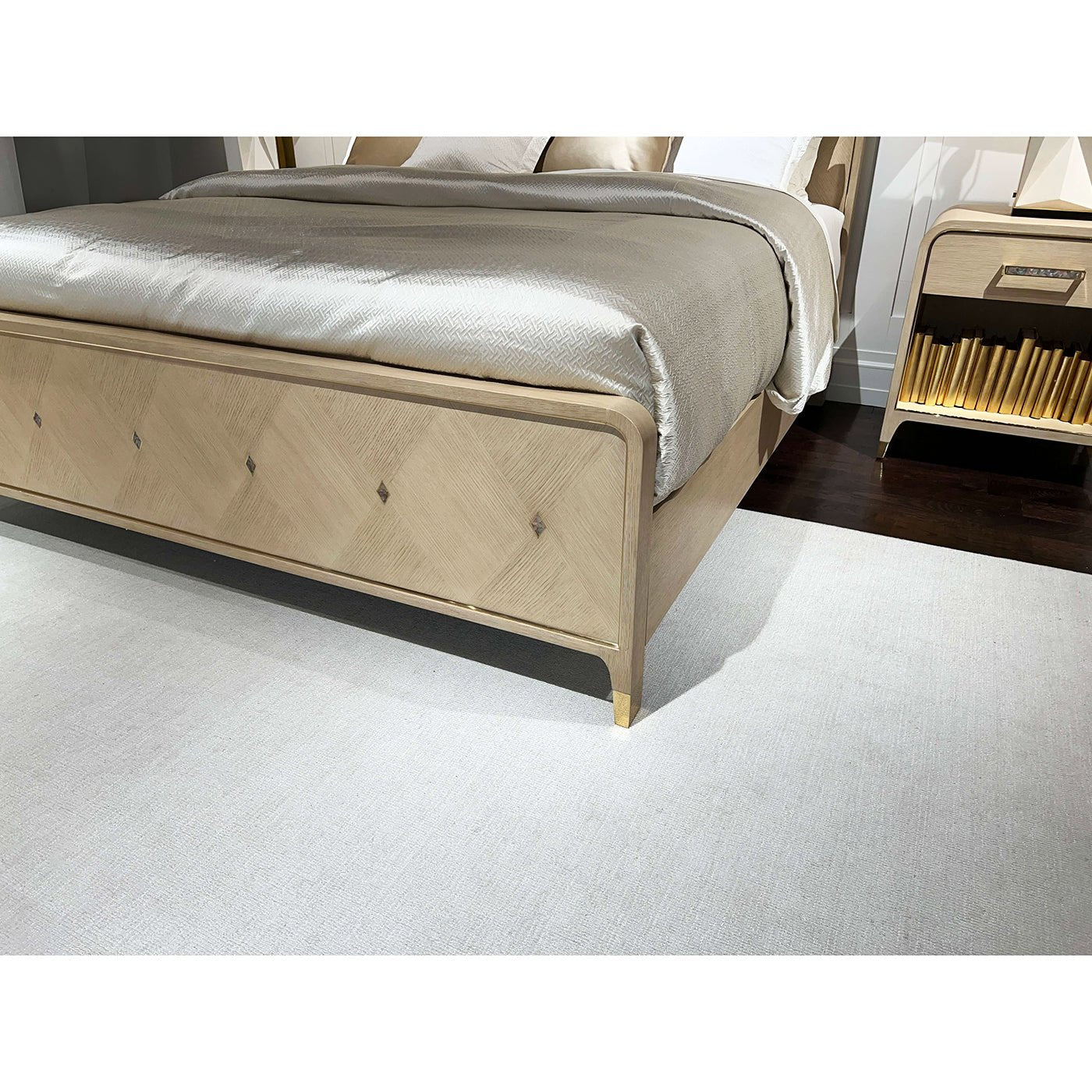 Footboard of Hollywood Regency king bed, close-up, floor rug visible.