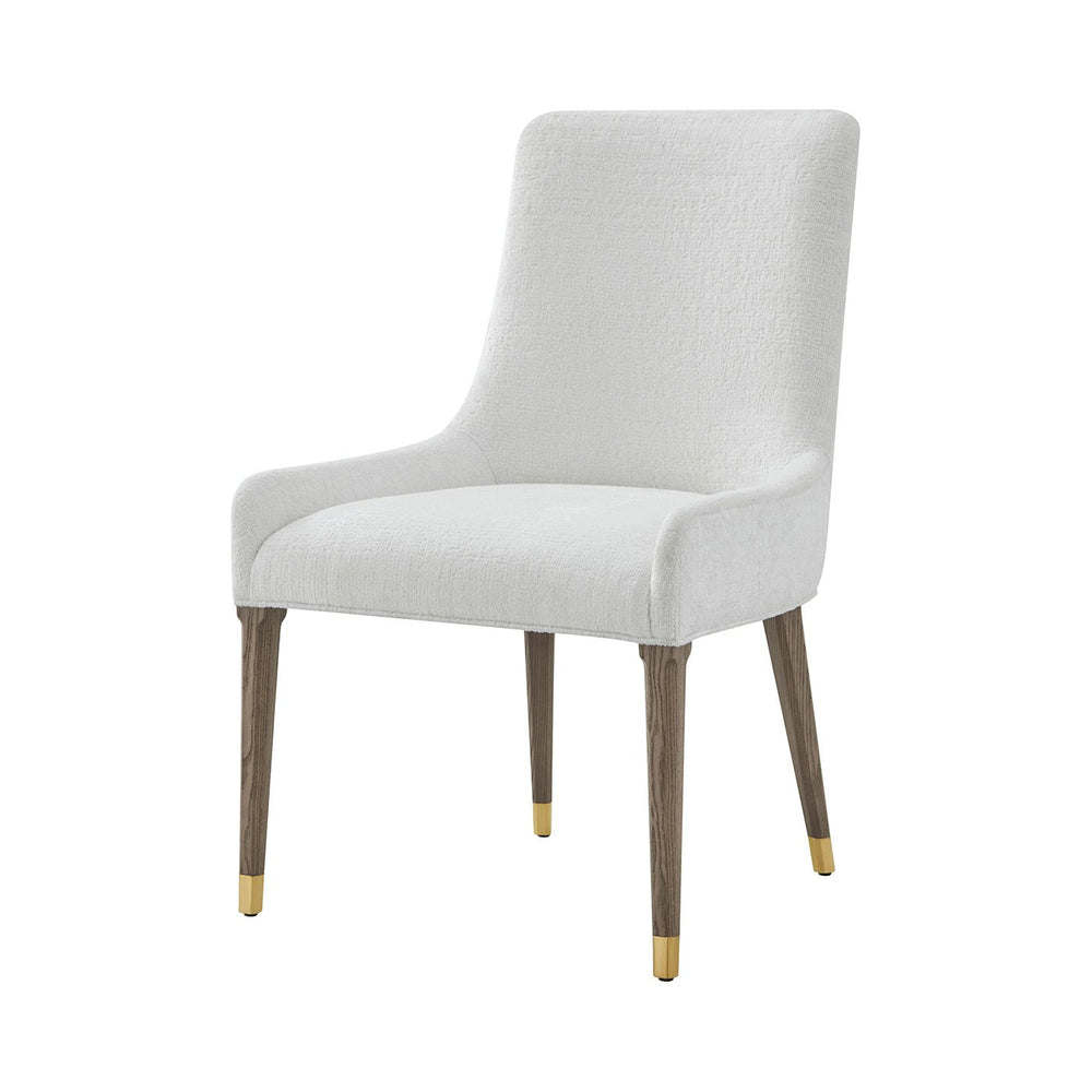 White upholstered dining chair with gold accents, front view.