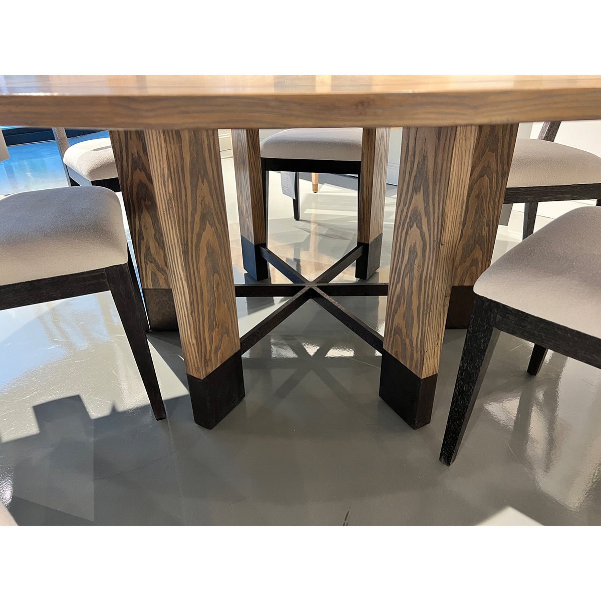 Dining table base with cross supports and chairs.